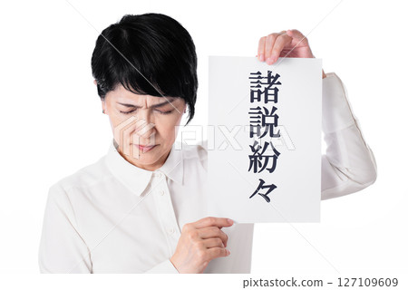 A middle-aged woman with her head down, holding a piece of paper with various theories written on it A middle-aged woman with her head down, holding a piece of paper with various theories written on it 127109609