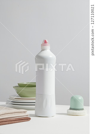 White dish washing bottle standing upright on a dining setup with plates and soft-hued props, reflecting minimal kitchen hygiene concept. Space for design, vertical frame for social ads White dish washing bottle standing upright on a dining setup with plates and soft-hued props, reflecting minimal kitchen hygiene concept. Space for design, vertical frame for social ads 127110021