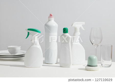 Group of spray bottles, dish soap, and glasses arranged on a bright white table, representing essential cleaning products for the home. Mockup product with blank space for design label Group of spray bottles, dish soap, and glasses arranged on a bright white table, representing essential cleaning products for the home. Mockup product with blank space for design label 127110029
