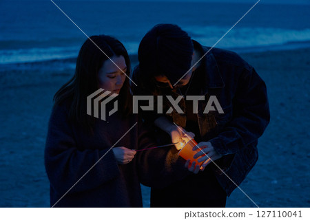 夜晚,年輕男女在海灘上玩手持煙火 夜晚,年輕男女在海灘上玩手持煙火 127110041