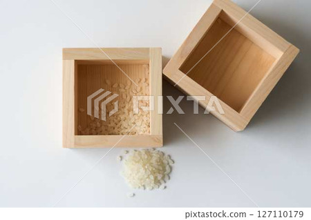 木箱中的少量米和白色背景上灑出的米飯 127110179