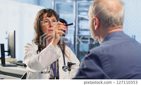 Professional medic examining patient reaction to light for pupil response during concussion assessment, checking for dizziness, light sensitivity and balance issues. Trauma checkup. Camera B. Professional medic examining patient reaction to light for pupil response during concussion assessment, checking for dizziness, light sensitivity and balance issues. Trauma checkup. Camera B. 127110353