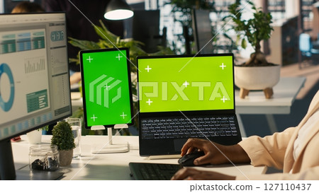 Mockup tablet and laptop in office used by employee working on company administrative tasks. Chroma key devices on desk used by worker reviewing business data metrics, camera A Mockup tablet and laptop in office used by employee working on company administrative tasks. Chroma key devices on desk used by worker reviewing business data metrics, camera A 127110437