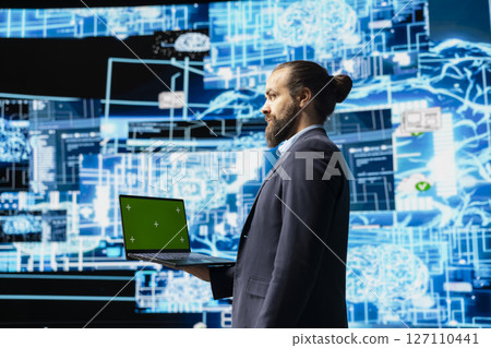 Business administrator uses mockup display next to AI neural networks system, practicing machine learning and cloud computing. Young man implementing artificial intelligence brain. Business administrator uses mockup display next to AI neural networks system, practicing machine learning and cloud computing. Young man implementing artificial intelligence brain. 127110441