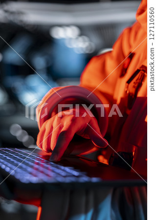 Close up of astronaut typing on laptop keyboard, troubleshooting red light warning triggered by system error. Spaceship cosmonaut using notebook to fix error affecting operations 127110560