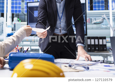 Shareholders reading report of industrial production growth opportunities and technological insights found during research and development process. Factory manager offers investors documentation files 127110579