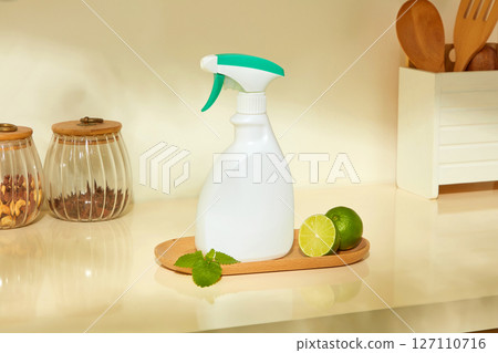 A spray bottle and fresh lemon placed on a cutting board in a warm kitchen space highlight the natural ingredients in a daily cleaning routine. Lime-scented or lime-infused products 127110716