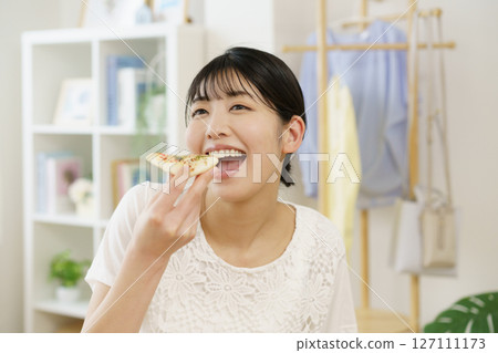 Young woman preparing to eat pizza in the living room 127111173