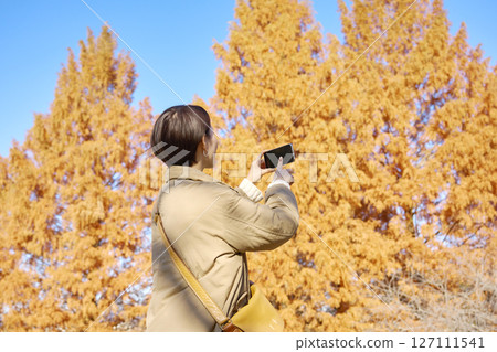 一位中年婦女正在拍攝秋葉的背影 127111541