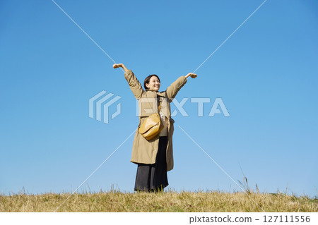 Woman, middle age, stretching, blue sky, whole body Woman, middle age, stretching, blue sky, whole body 127111556