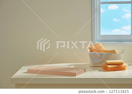 Kitchen counter with wooden board, folded cloth, and dishes arranged under a bright sky view window, evoking a serene and tidy atmosphere. 127111825