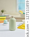 On a minimalist kitchen background with many tools for cleaning the kitchen, a green product bottle without label is placed in the center, no label for branding design, kitchen cleaning products 127111859