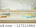 Bright kitchen sink area with stacked dishes, a sponge, and cleaning cloths styled to portray a peaceful yet functional cleaning routine. Kitchen background and blank space for design 127111860