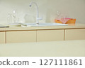Minimalist countertop with wine glasses, a pink cloth, and a translucent spray bottle, lit by soft morning sunlight through the window. 127111861