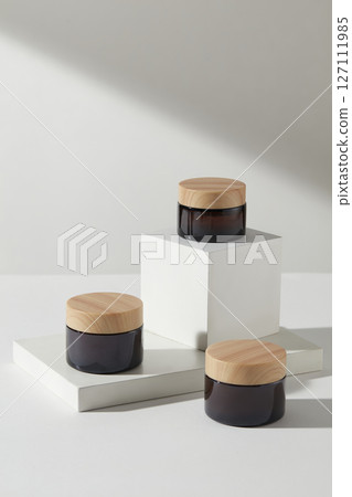 Cosmetics advertising scene with minimalist concept. Three cosmetic jars no label displayed on white podium on a white background. Mock up packaging, cosmetics design Cosmetics advertising scene with minimalist concept. Three cosmetic jars no label displayed on white podium on a white background. Mock up packaging, cosmetics design 127111985