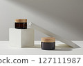 Front view of twp amber cosmetic jars unlabeled decorated with white podiums on a white background. Minimal scene for advertising cosmetic product with space for design label 127111987
