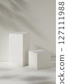 Front view of two white empty podiums displayed on a white background with natural leaves shadow. Blank minimalist empty showcase template 127111988