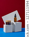 Cosmetics jar and serum bottle no label mockup for design displayed on white geometries podiums on red and blue background. Front view, minimal scene for advertising cosmetic product 127111994
