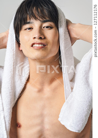 一名年輕男子用浴巾擦頭髮 一名年輕男子用浴巾擦頭髮 127112176