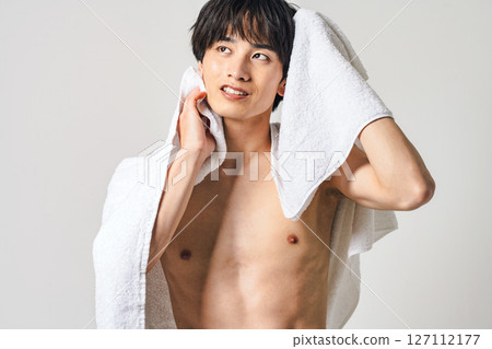 A young man wiping his hair with a bath towel 127112177