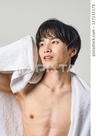 一名年輕男子用浴巾擦頭髮 一名年輕男子用浴巾擦頭髮 127112178