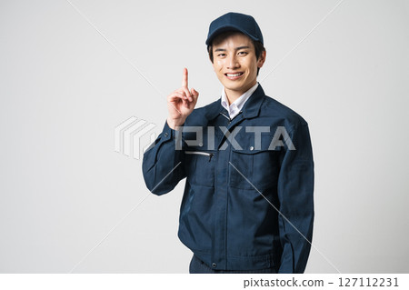 A young man in his 20s wearing work clothes and pointing A young man in his 20s wearing work clothes and pointing 127112231