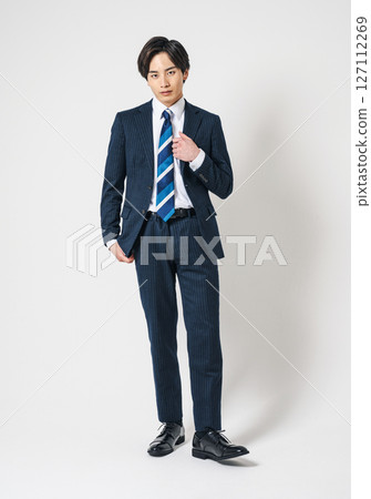 Full body portrait of a young businessman standing in a suit 127112269