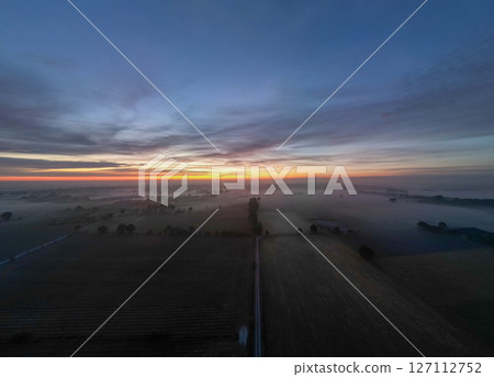 A Stunning Sunrise Over Foggy Fields Awash with Vibrant Colors Glowing Beautifully 127112752