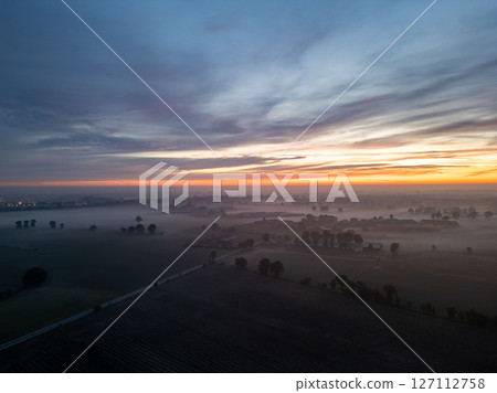 Witness the breathtaking beauty of a stunning sunrise illuminating the misty fields below Witness the breathtaking beauty of a stunning sunrise illuminating the misty fields below 127112758