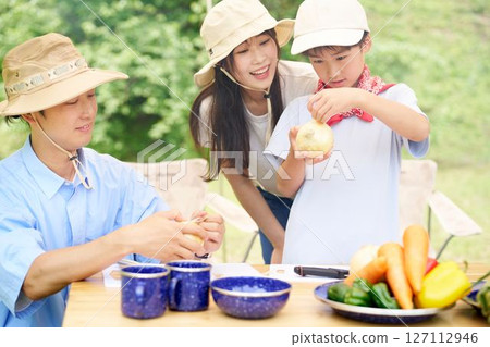 Family preparing vegetables at a campsite 127112946