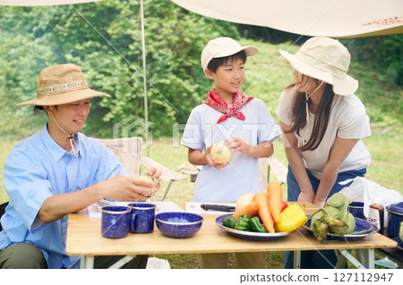 Family preparing vegetables at a campsite Family preparing vegetables at a campsite 127112947