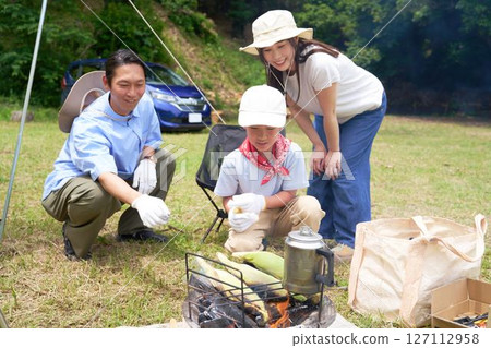 Parents watch as children try outdoor cooking 127112958