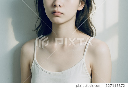 Young woman leaning against a wall in the morning light 127113872