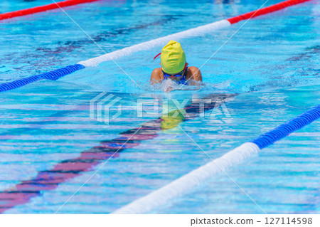 Swimmer child swims breaststroke swimming style in a race swimming pool. Water sports and competition, learning to swim classes for children. 127114598