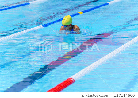 Swimmer child swims breaststroke swimming style in a race swimming pool. Water sports and competition, learning to swim classes for children. Swimmer child swims breaststroke swimming style in a race swimming pool. Water sports and competition, learning to swim classes for children. 127114600