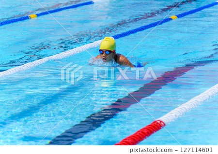 Swimmer child swims breaststroke swimming style in a race swimming pool. Water sports and competition, learning to swim classes for children. 127114601