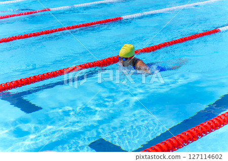 Swimmer child swims breaststroke swimming style in a race swimming pool. Water sports and competition, learning to swim classes for children. Swimmer child swims breaststroke swimming style in a race swimming pool. Water sports and competition, learning to swim classes for children. 127114602
