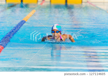 Swimmer child swims butterfly swimming style in a race swimming pool. Water sports and competition, learning to swim classes for children. 127114605