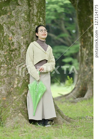 Japanese woman sheltering from the rain under a tree Japanese woman sheltering from the rain under a tree 127114775