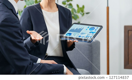 一群男女商務人士在大廳一邊看平板電腦一邊討論業務 127114837