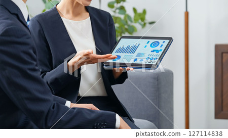 一群男女商務人士在大廳一邊看平板電腦一邊討論業務 127114838