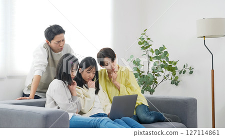 小學姊妹和她們的家人一邊看著筆記型電腦一邊擔心 127114861