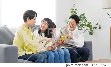 A family of elementary school girls looking at a smartphone with a smile 127114875