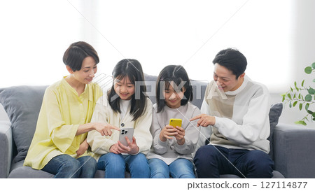 A family of elementary school girls looking at a smartphone with a smile A family of elementary school girls looking at a smartphone with a smile 127114877