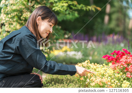 園林綠化產業和公園管理部門身穿工作服的女士正在檢查公園內的花壇。 127116305