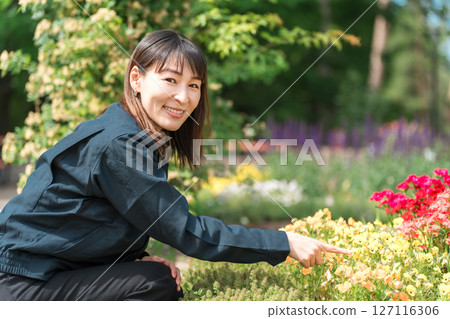 園林綠化產業和公園管理部門身穿工作服的女士正在檢查公園內的花壇。 127116306
