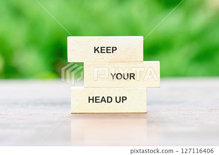 Concept words KEEP YOUR HEAD UP painted on wooden blocks on a bright green background, reflecting the peaceful atmosphere outdoors 127116406