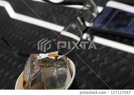 Candy wrapper in a paper cup of coffee. 127117267