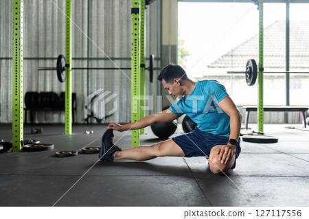 Fitness Stretching. Man reaching for his foot in a gym environment. Fitness Stretching. Man reaching for his foot in a gym environment. 127117556