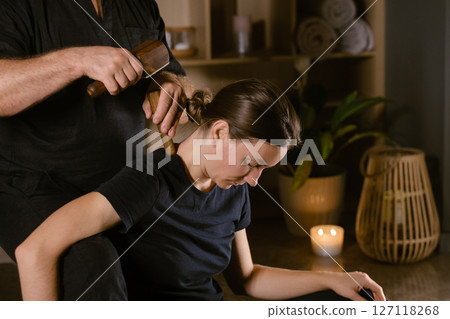 Male master giving Thai Toksen massage to girl in massage room. A girl gets a relaxing Thai back massage with a Toxen massage kit Male master giving Thai Toksen massage to girl in massage room. A girl gets a relaxing Thai back massage with a Toxen massage kit 127118268